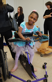 Young girl practices ballet with help of assistive device.